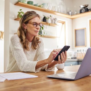 Mature Woman Calls A Non-Profit Debt Management Program On A Smartphone