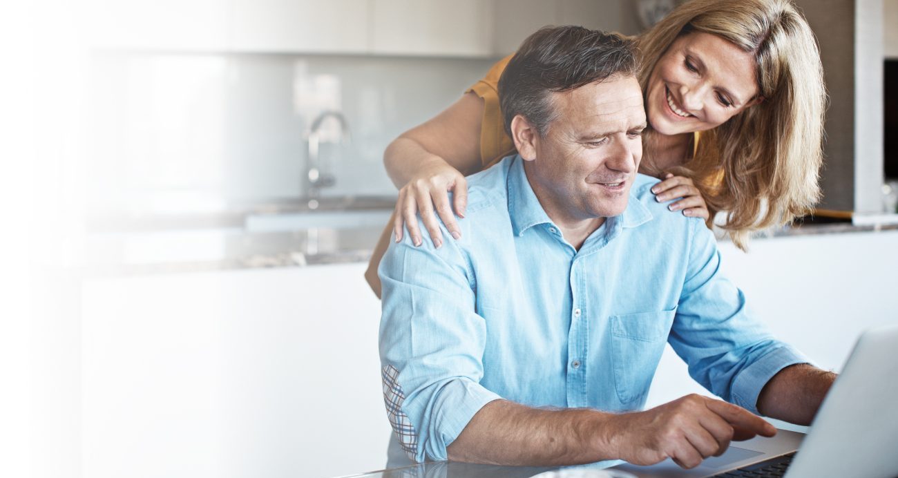 a happy couple using a laptop in their modern kitchen