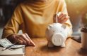 Woman putting money in piggy bank