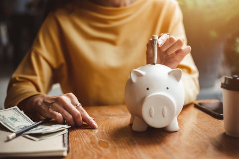 Woman putting money in piggy bank